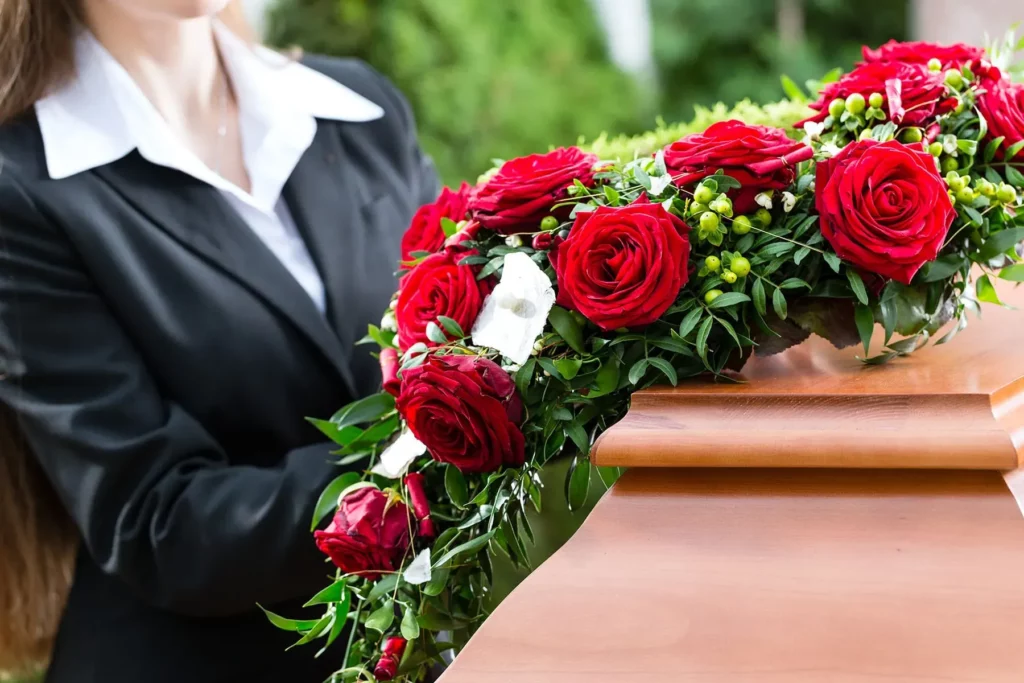 Agente funéraire portant un bouquet de roses rouges destiné à orner un cercueil.