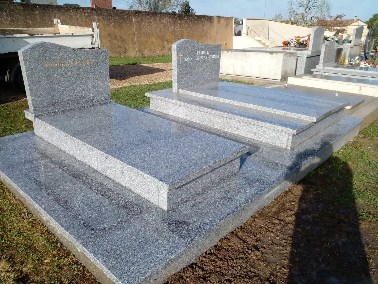 Sépultures familiales en granit gris installées côte à côte dans un cimetière.